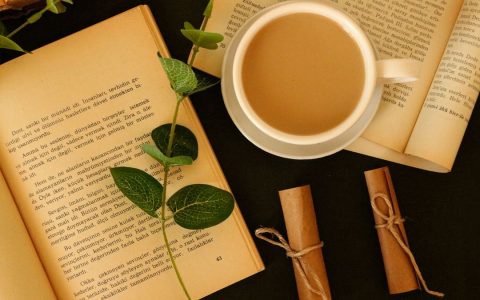 Cozy still life with coffee, open books, and green leaves for a relaxing reading time.