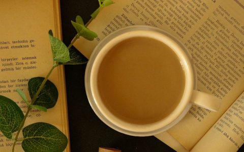 Warm coffee cup surrounded by books and leaves, perfect for a cozy setting.