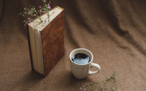 A warm, serene setup with a book, coffee cup, and delicate flowers.