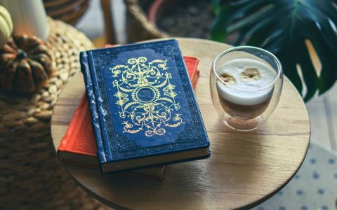 Warm and inviting setup featuring ornate books, a glass of frothy coffee, and natural decor.