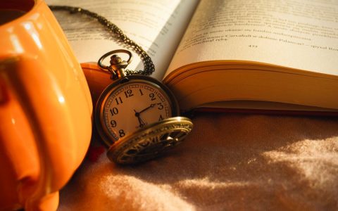 Aesthetic still life featuring a vintage pocket watch, an open book, and a warm cup, perfect for cozy autumn vibes.