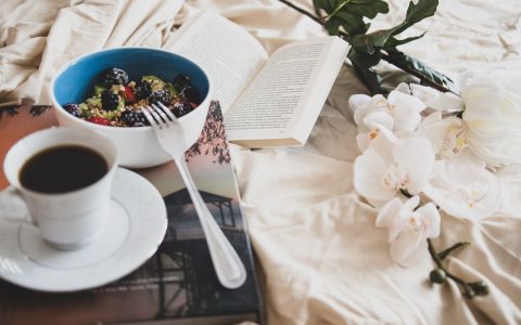Relax with a book, a cup of coffee, and a fresh fruit bowl on a cozy morning.