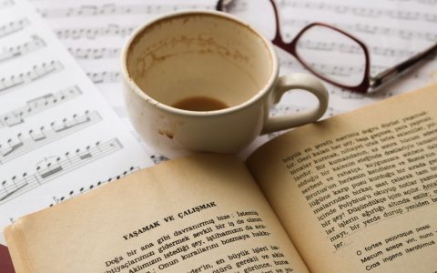 A cozy scene with a cup of coffee, an open book, and sheet music for relaxation.
