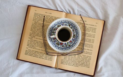 Cozy flatlay featuring a book, coffee cup, and glasses. Perfect for relaxation themes.
