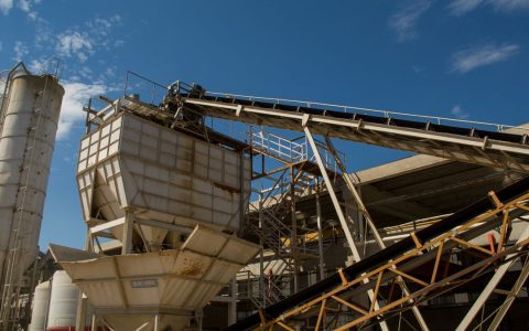 View of rusty machinery and structures at an industrial plant in Córdoba under a clear blue sky.