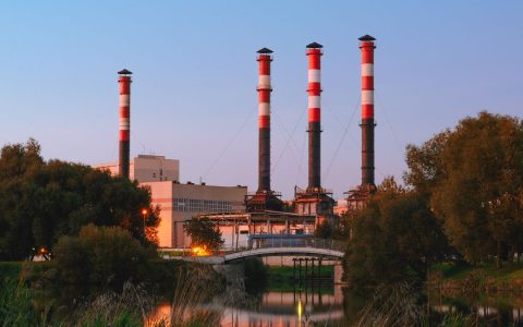 View of an industrial plant with tall chimneys by a lake in Minsk, Belarus during the day.