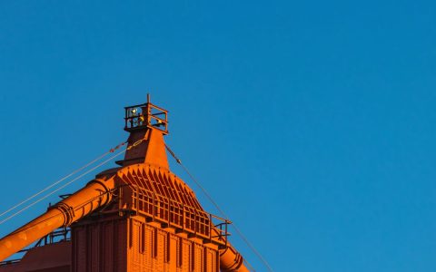 An industrial structure with pipes against a clear blue sky, perfect for business or industrial themes.
