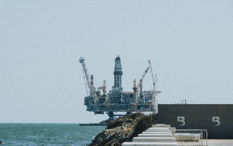 Distant view of an offshore oil rig with cranes on a sunny day.