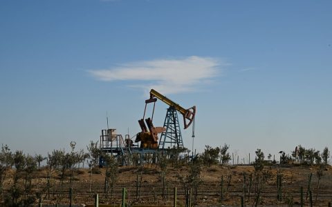Oil pump jack in a dry landscape with shrubs and clear sky in Bakú, Azerbaijan.
