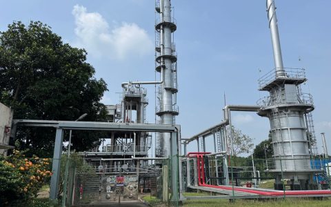 A large industrial plant outdoors with metal structures and clear blue sky.