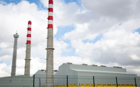 Factory chimneys against a blue sky symbolize industrial power and environmental impact.