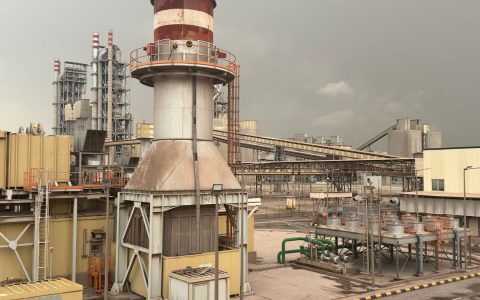 A large industrial facility on a cloudy day in Saudi Arabia, showcasing structures and machinery.