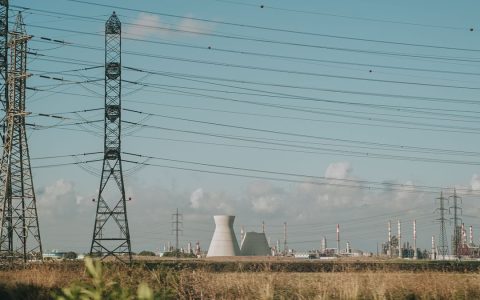 Scenic view of high voltage towers and power plant against a clear sky over dry grassland.