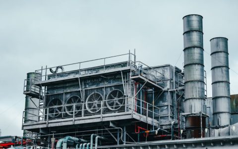 Exterior view of large industrial construction with metal tubes located on factory in daytime on cloudy weather
