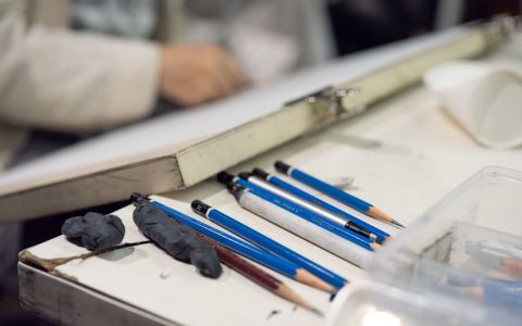 Close-up of art supplies and sketching pencils on a desk, suggesting a creative workspace.