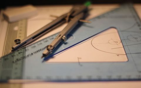 Precision drafting tools including compass and set square on a sketchpad.