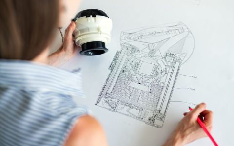 Female engineer studying a detailed technical blueprint at her workspace. Concept of design and innovation.