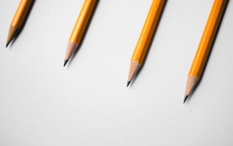 Minimalist image of four yellow pencils arranged diagonally on a white background.
