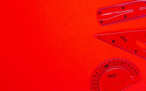 Red transparent rulers, set square, and protractor on vivid red background, ideal for educational and design content.