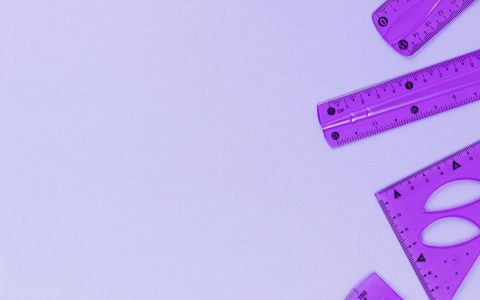 Purple rulers and protractors on a minimalist background with ample copy space.