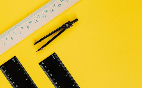 Vibrant still life of compass and rulers on a yellow background.