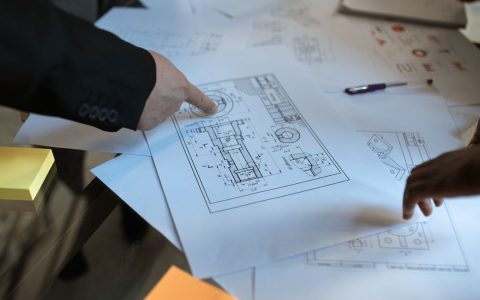 Engineers discussing blueprints at a workspace, focusing on teamwork and architecture design.