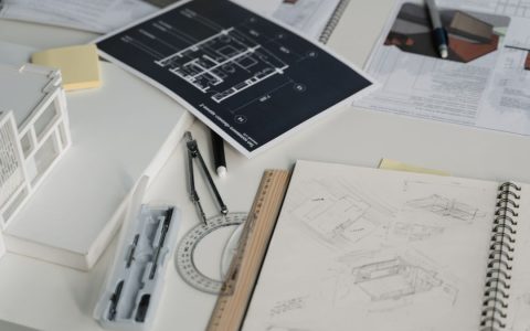 High-angle view of a desk with blueprints, sketches, and architectural tools.
