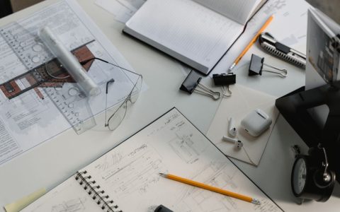 A busy architectural workspace featuring blueprints, sketches, and drafting tools.