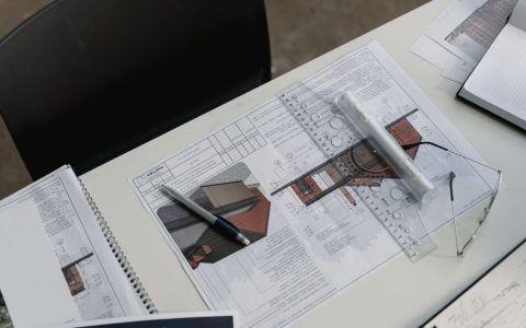 Top view of architectural blueprints and drafting tools on a workspace desk.