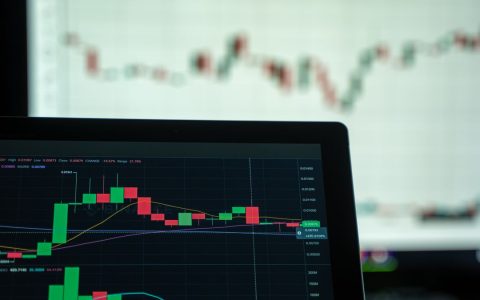 A laptop displays a detailed cryptocurrency trading chart with candlestick patterns.