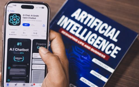 Smartphone displaying AI app with book on AI technology in background.