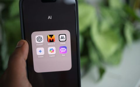 Close-up of a hand holding a smartphone with AI applications on screen.