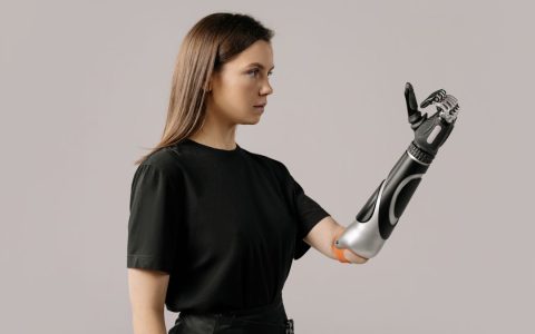 Portrait of a woman with a prosthetic arm wearing a black shirt. Studio lighting.