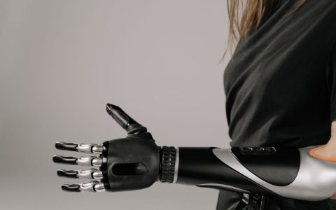 Close-up of a woman wearing a sleek, modern prosthetic arm. Studio shot emphasizes technology and innovation.