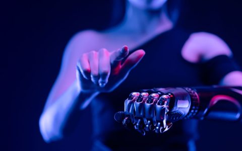 Close-up of a robotic hand with a woman pointing, showcasing advanced prosthetic technology.