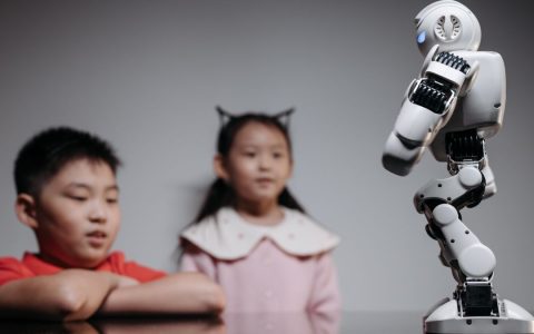 Two children watching and interacting with an innovative robot toy indoors.