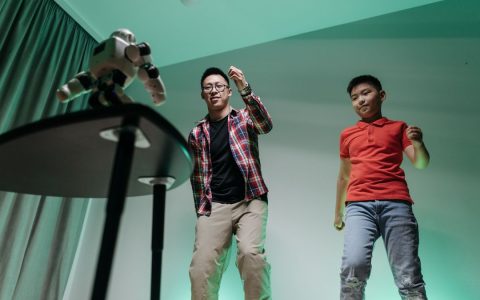 Father and son enjoying a fun dancing session with a robot in their living room.