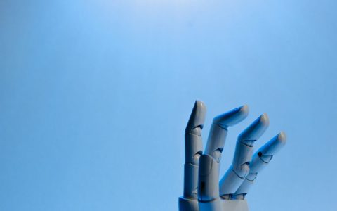Robotic hand with articulated fingers reaching towards the sky on a blue background.