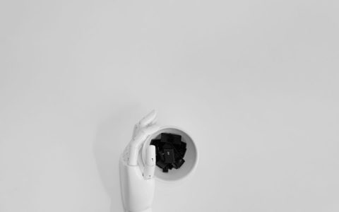 A robotic hand grasping black keyboard keys in a minimalist setting.
