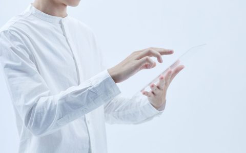 Person interacting with a transparent digital tablet, symbolizing technology and futurism.