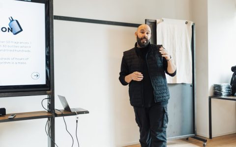 Professional giving a presentation in a modern office environment with a screen and laptop.