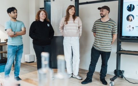 A team of diverse individuals presenting at a business meeting in a modern office setting.