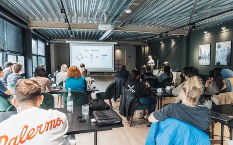 A diverse group attending an educational workshop indoors, focused on a presentation.