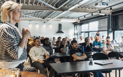 A dynamic speaker engaging a diverse audience in a modern workshop setting.