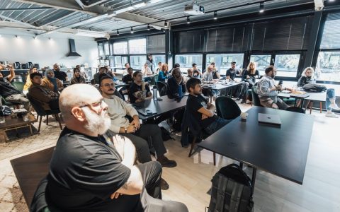 A diverse group of professionals attentively listening during an indoor business meeting in a modern conference room.