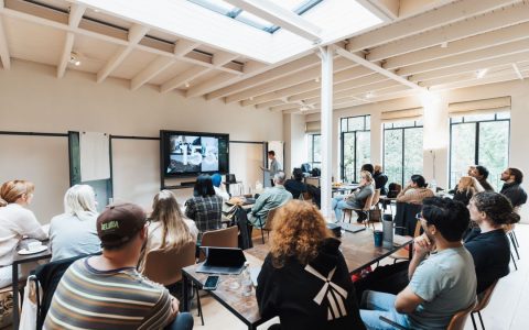 A group of adults attending a business workshop in a spacious modern room with natural light.