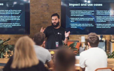 Professional speaker discusses 3D printing applications with attentive audience in tech seminar.