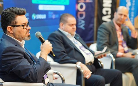 Three men engaged in a panel discussion at a professional conference.