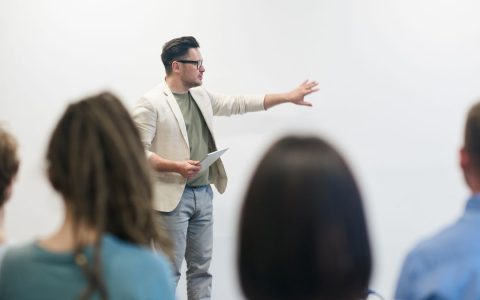 A man in a blazer gives a presentation to a captivated audience in a lecture setting.