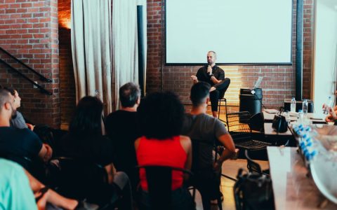 A dynamic seminar with a speaker engaging a diverse audience in a modern indoor setting.